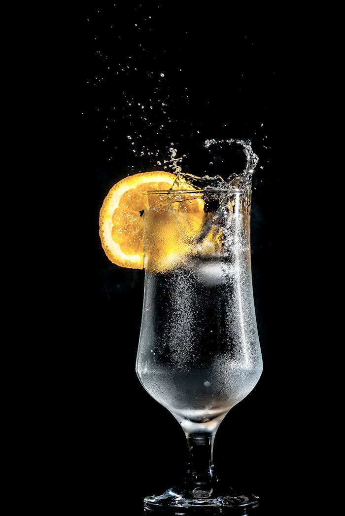 Dart Bar mit Cocckails Dazzling cold cocktail with citrus slice splash, set against a dramatic black background.