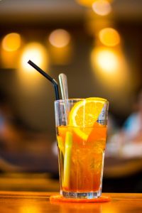 A vibrant orange iced tea garnished with fresh citrus slices in a lively indoor setting.