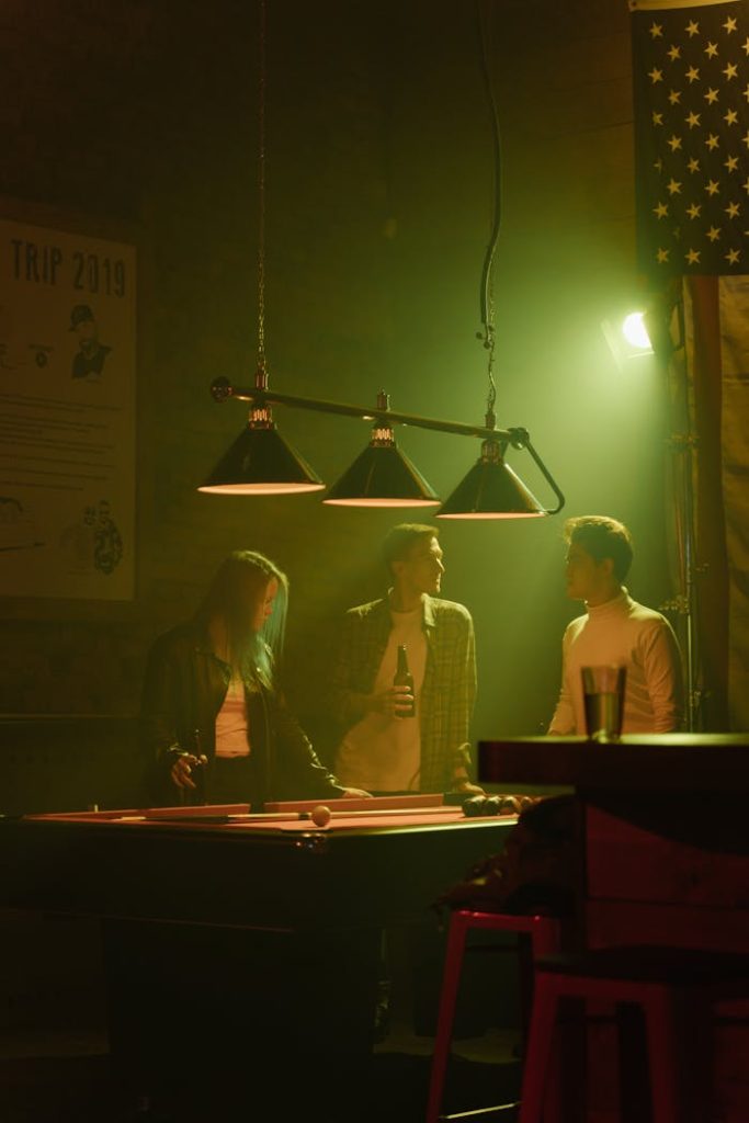 people-in-a-sports-bar-near-a-billiard-table-6530921 Group of friends enjoying a casual night indoors at a bar playing pool.